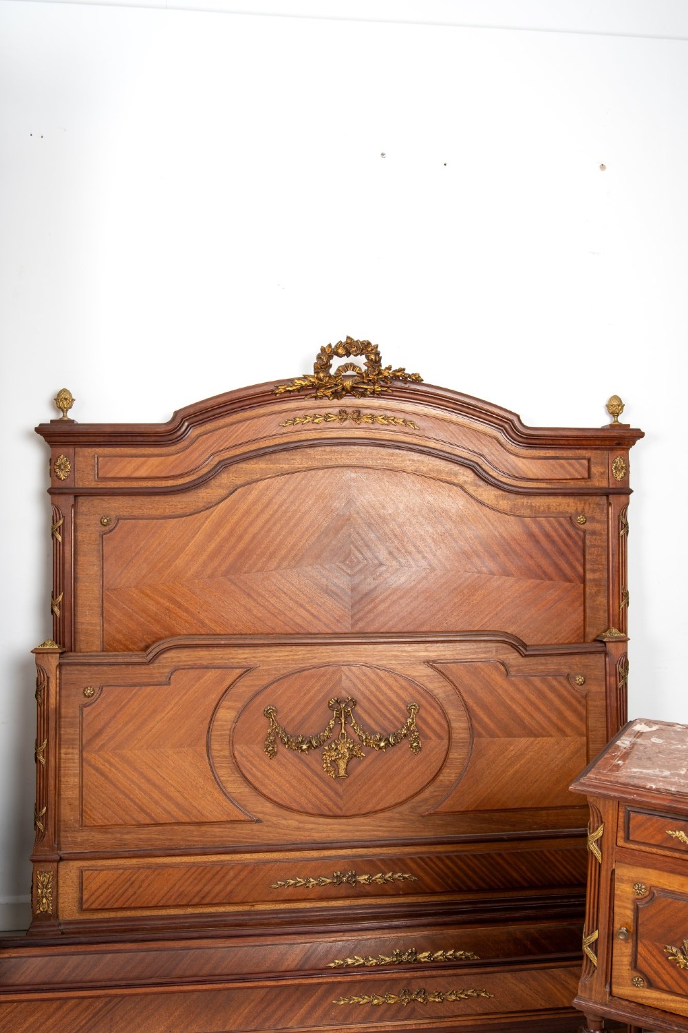 A French Louis XVI Revival mahogany bedroom suite comprising a mirrored two-door armoire, a matching bedframe with parquetry detailing, and a marble-topped bedside table with gilded bronze mounts. View V