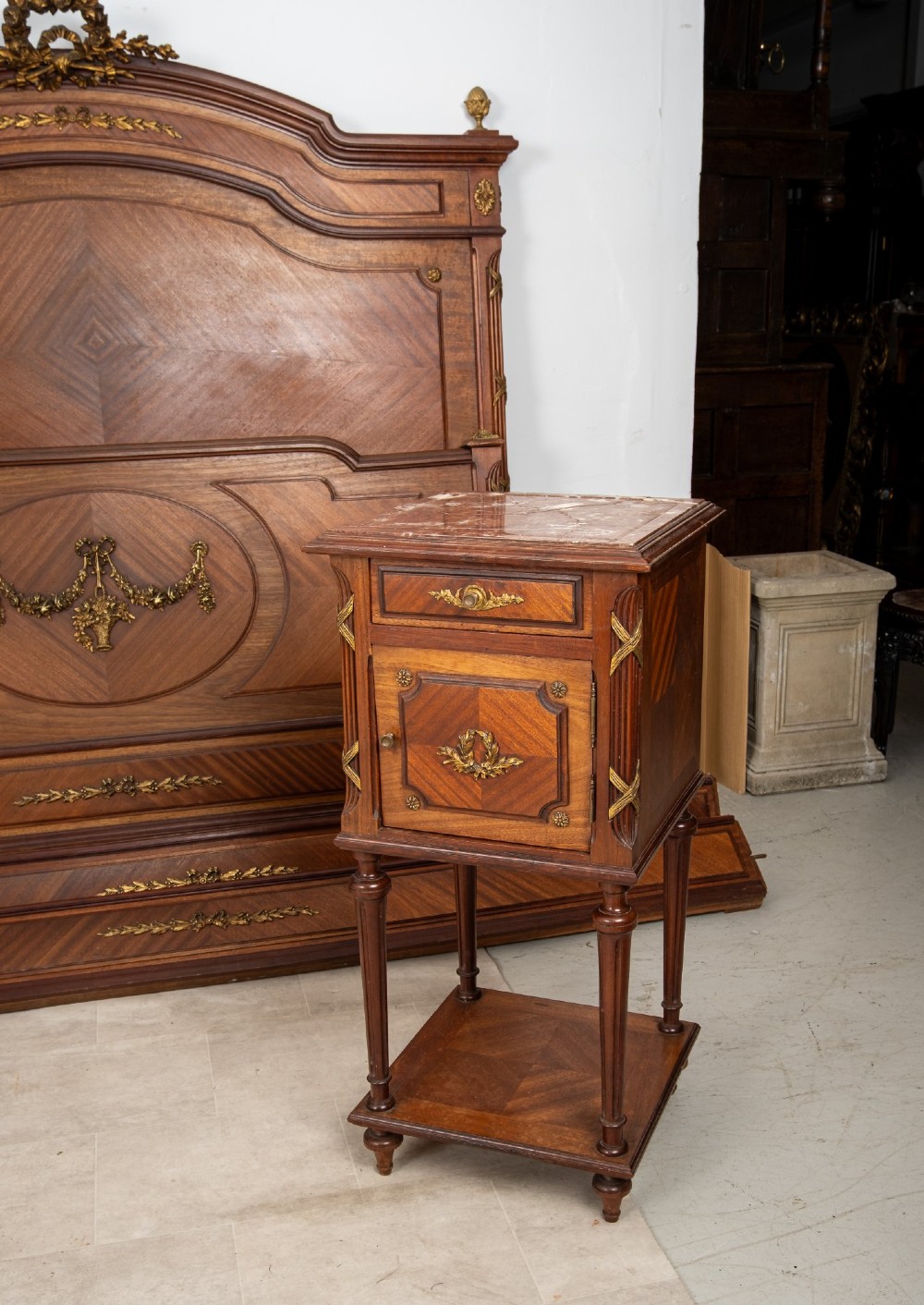 A French Louis XVI Revival mahogany bedroom suite comprising a mirrored two-door armoire, a matching bedframe with parquetry detailing, and a marble-topped bedside table with gilded bronze mounts. View VIII