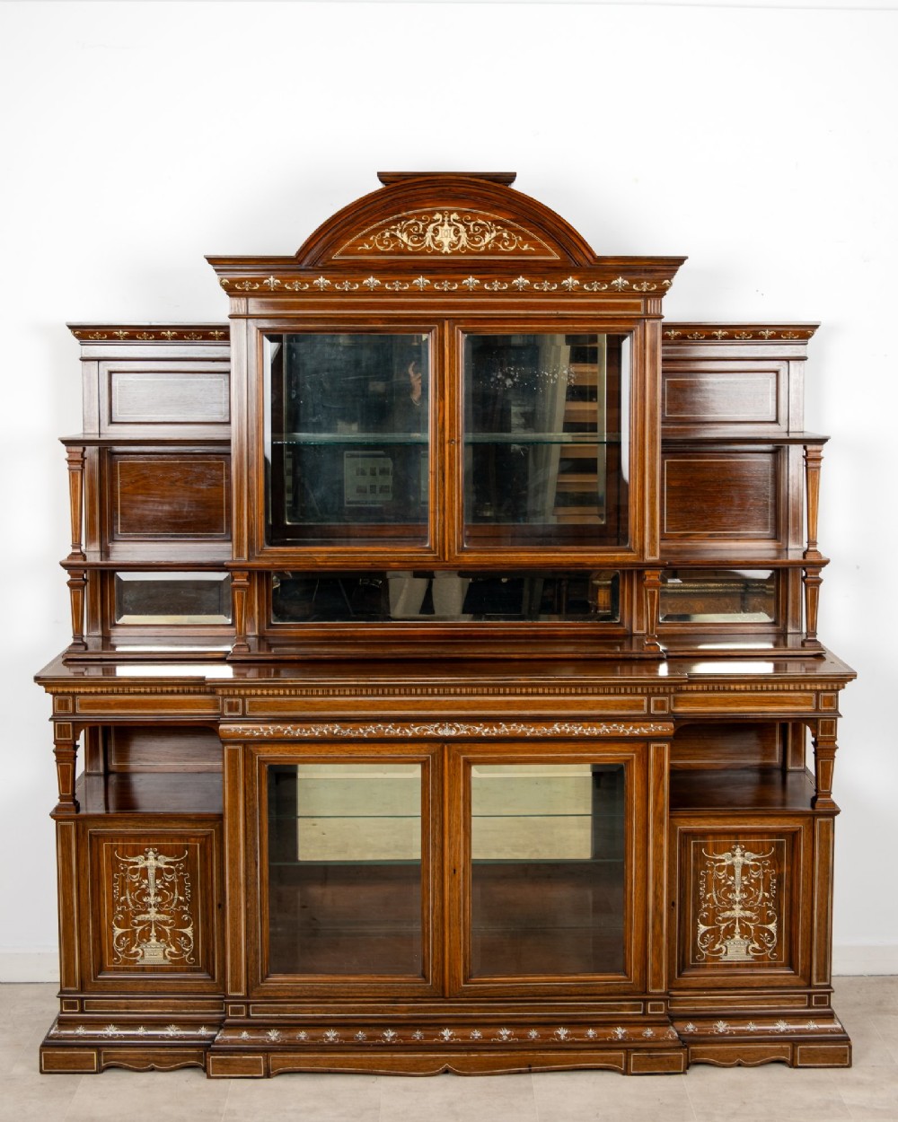 A large late Victorian rosewood display cabinet featuring intricate inlay work, glazed upper and lower doors, an arched pediment, and mirrored back panels. View II