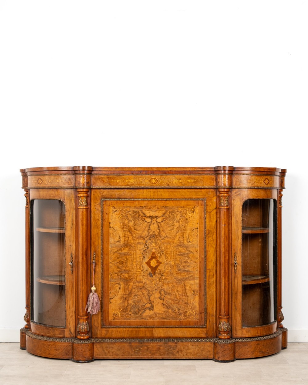 An antique Victorian burr walnut credenza featuring a central inlaid marquetry door flanked by two curved glazed display cabinets and gilt mounts. View II