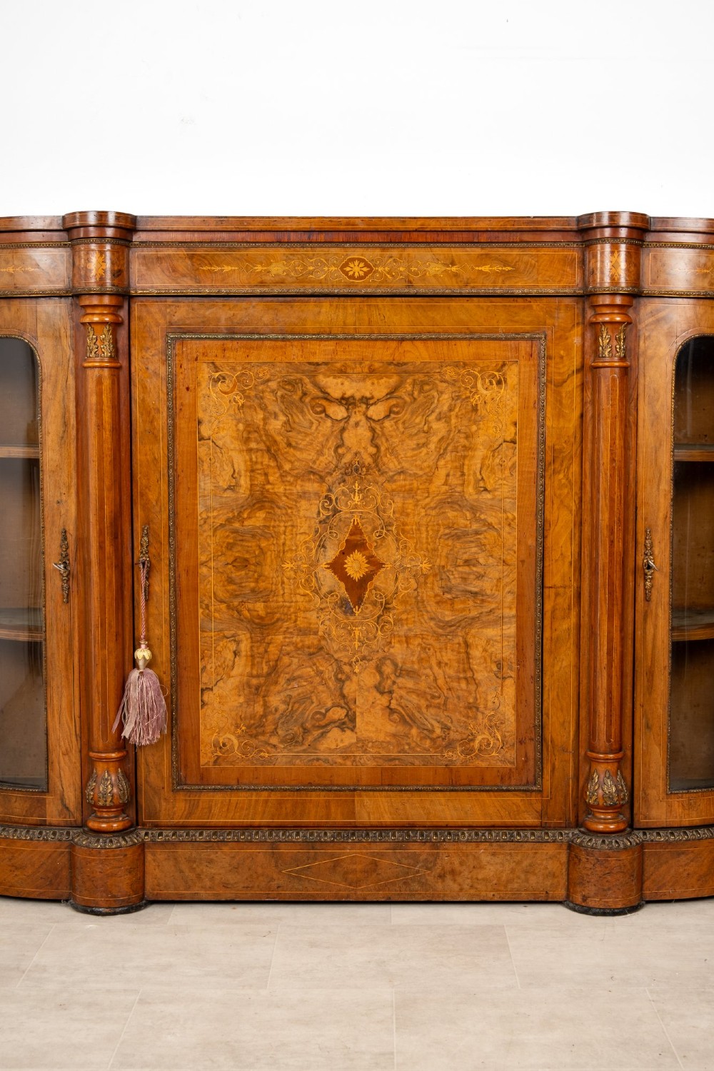 An antique Victorian burr walnut credenza featuring a central inlaid marquetry door flanked by two curved glazed display cabinets and gilt mounts. View IV