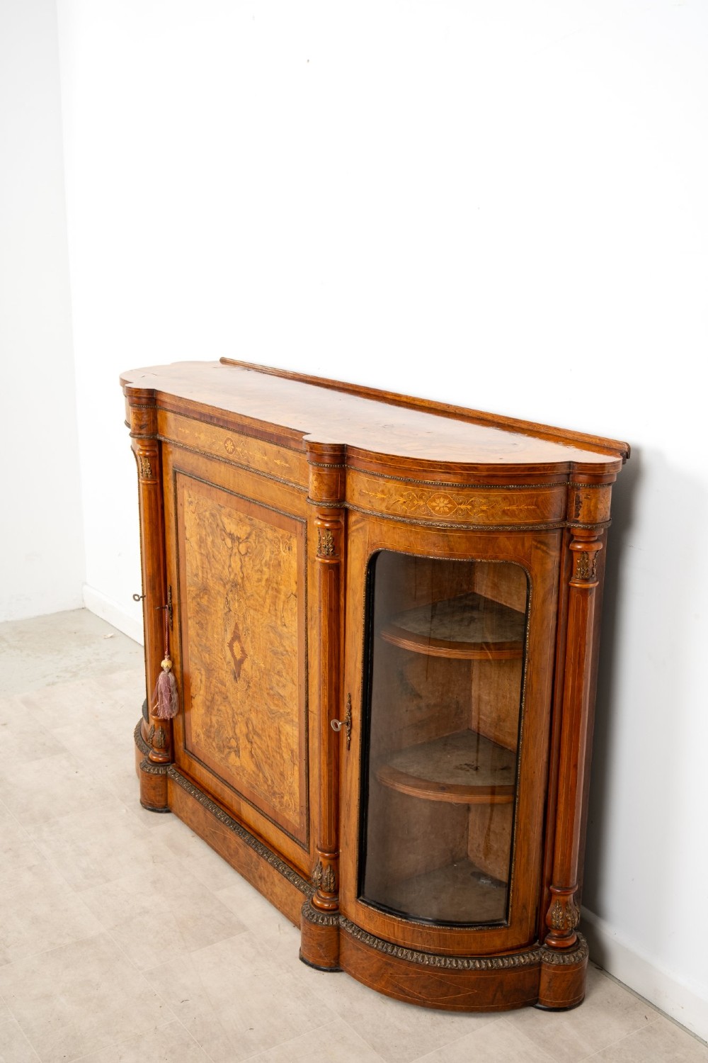 An antique Victorian burr walnut credenza featuring a central inlaid marquetry door flanked by two curved glazed display cabinets and gilt mounts. View V