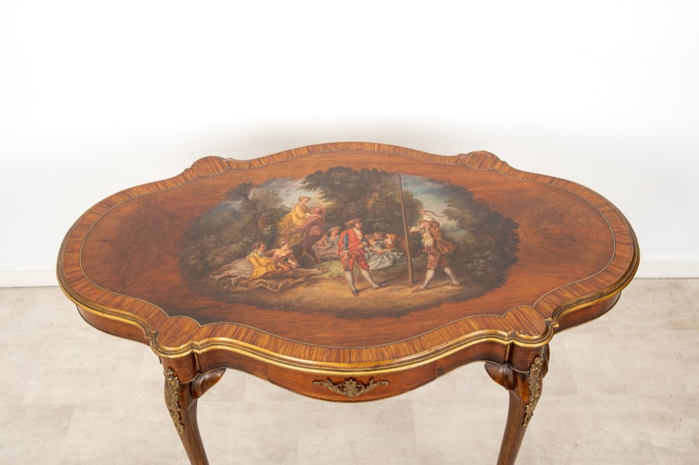 A French Louis XV style centre table featuring a serpentine glass-covered top with a painted figurative scene, cabriole legs, and ornate gilt bronze mounts. View II