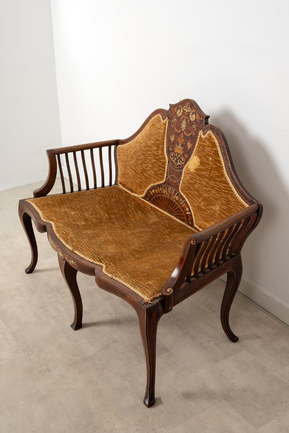 An Edwardian mahogany settee featuring floral marquetry inlay on a central back panel, slatted arms, cabriole legs, and gold-brown velvet upholstery. View V