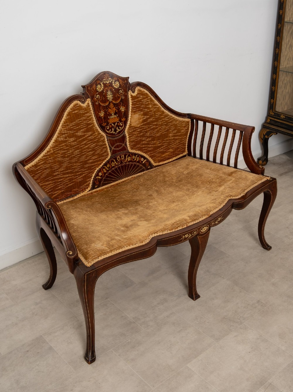 An Edwardian mahogany settee featuring floral marquetry inlay on a central back panel, slatted arms, cabriole legs, and gold-brown velvet upholstery. View VI