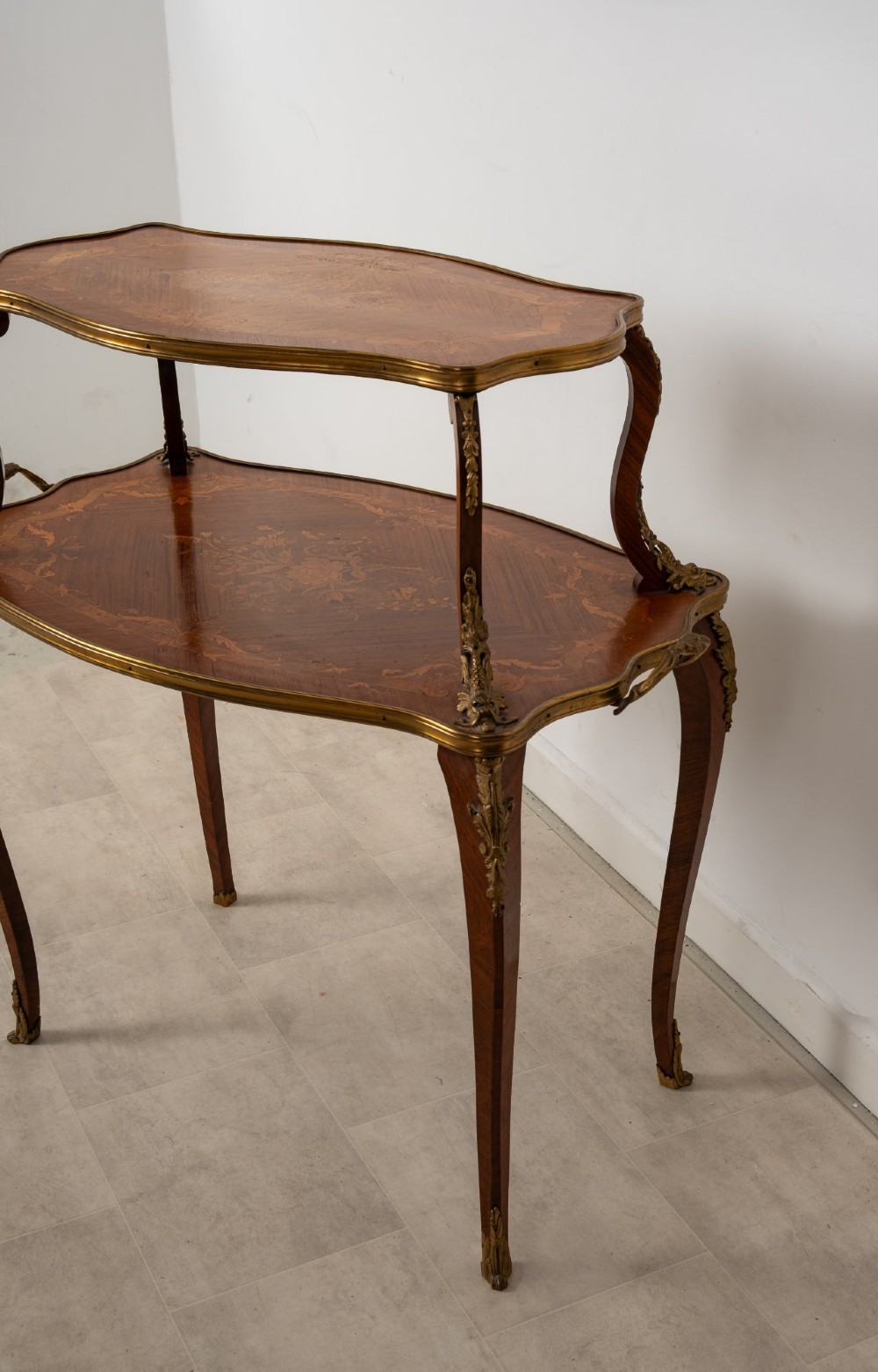 An antique Louis XV style two-tier kingwood side table featuring floral marquetry inlay, serpentine edges, and gilt-bronze mounts on cabriole legs. View VIII