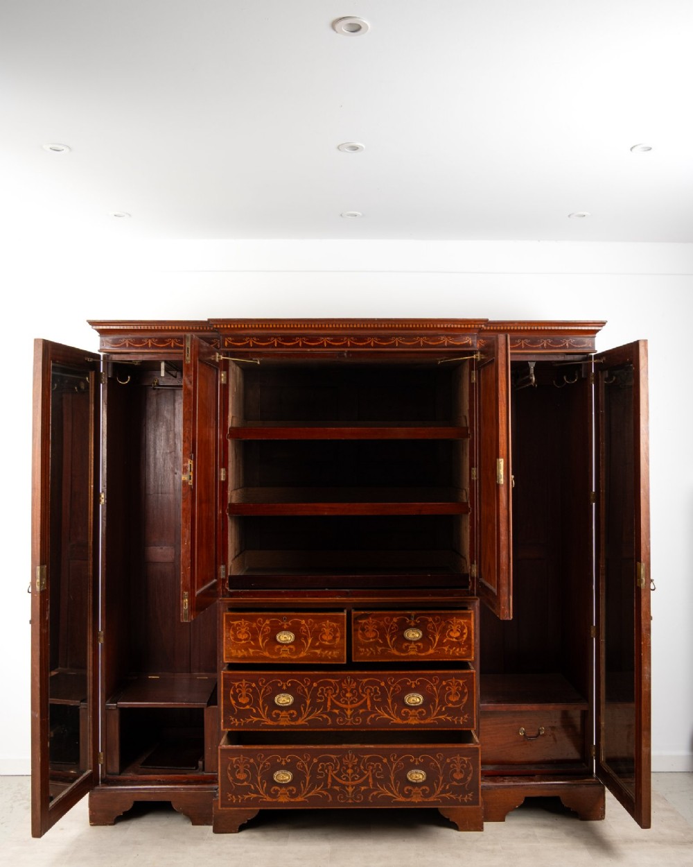 An Edwardian mahogany compactum wardrobe featuring classical urn marquetry inlay, side hanging sections, central drawers, and panelled cupboard doors. View VII
