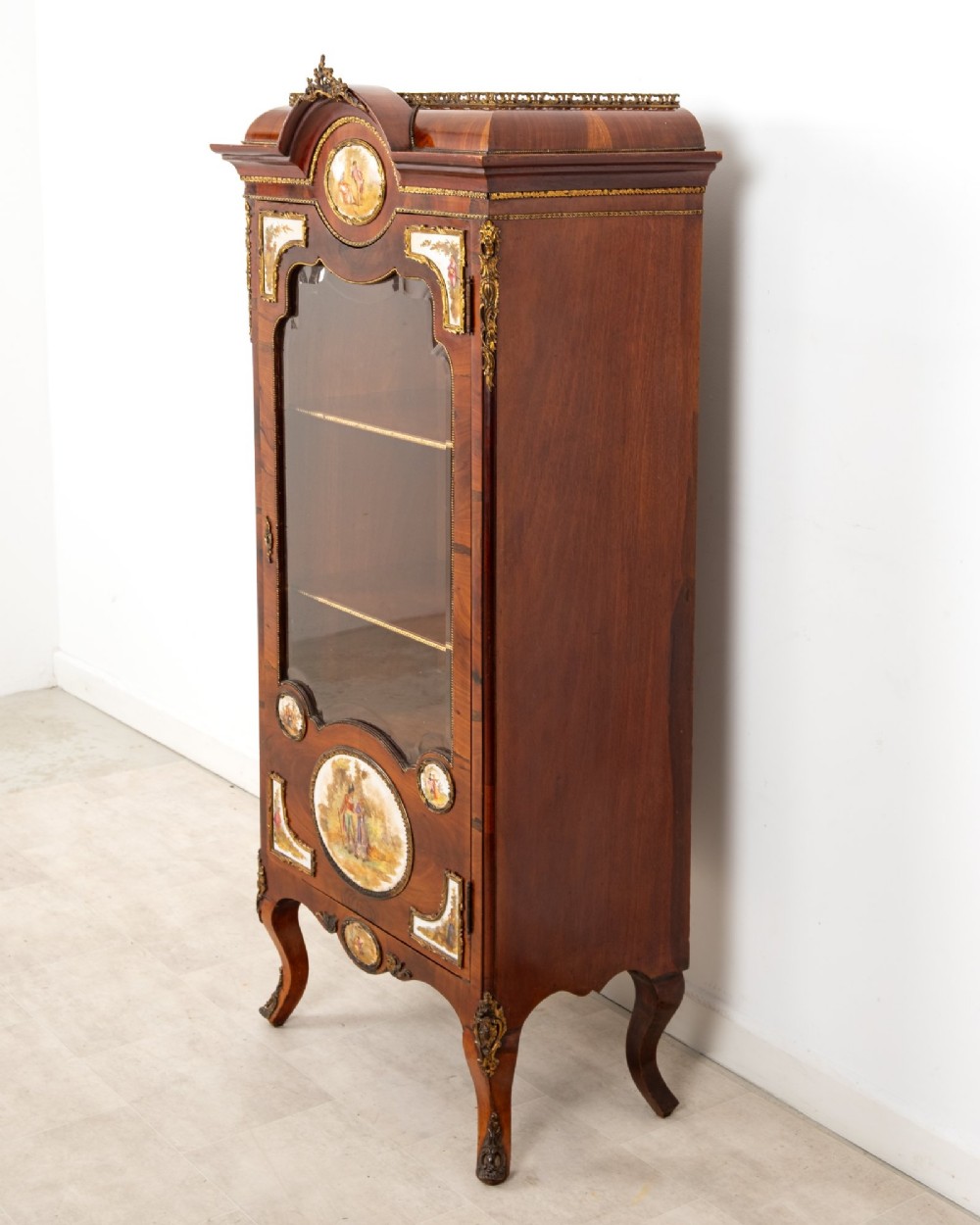An antique French walnut vitrine featuring a single glass door, hand-painted porcelain plaques, gilt-bronze ormolu mounts, and cabriole legs. View VII