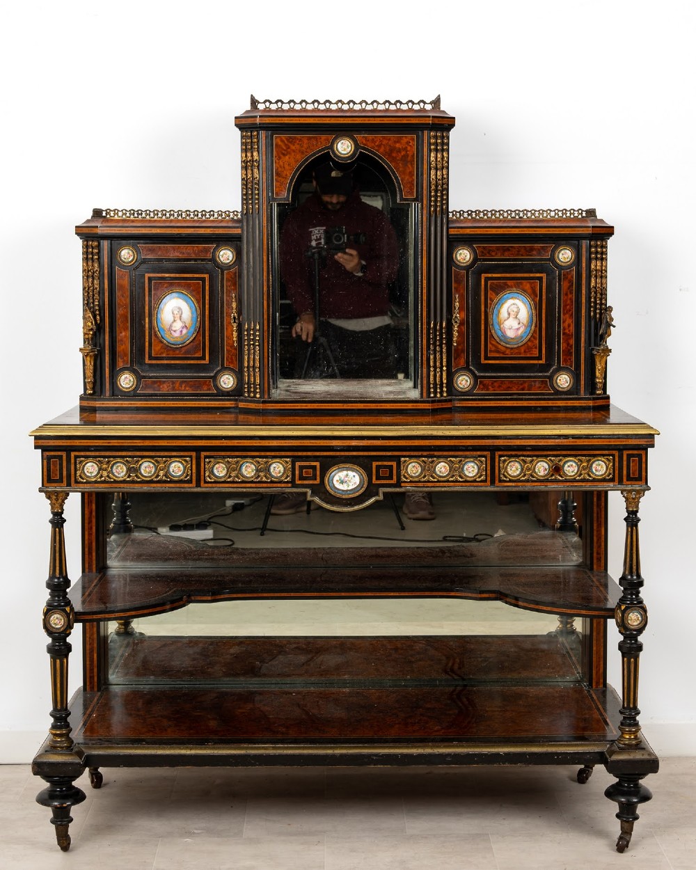 A nineteenth-century French ebonised and amboyna bonheur du jour desk featuring porcelain plaques, mirrored panels, turned legs, and brass mounts.