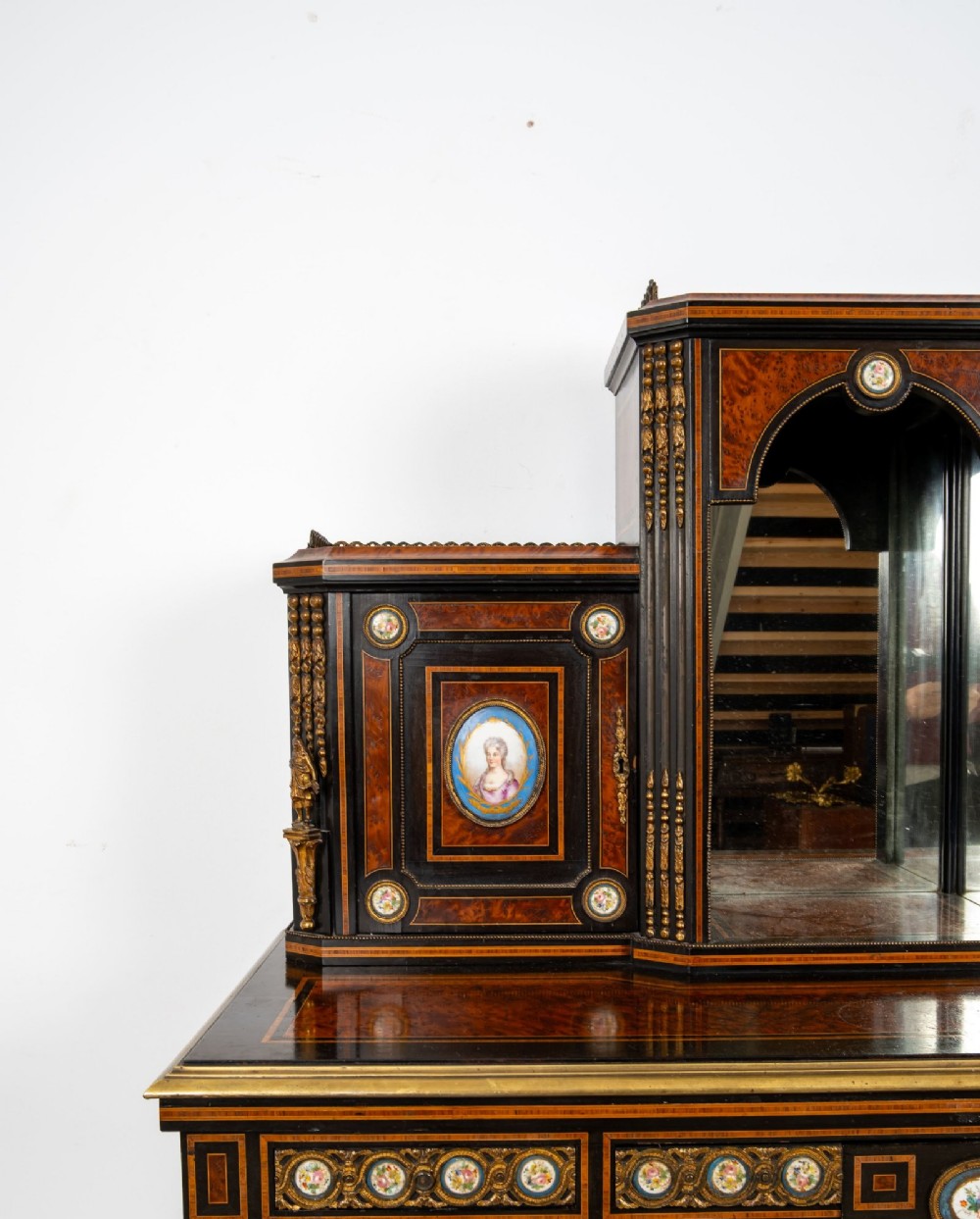 A nineteenth-century French ebonised and amboyna bonheur du jour desk featuring porcelain plaques, mirrored panels, turned legs, and brass mounts. View VI
