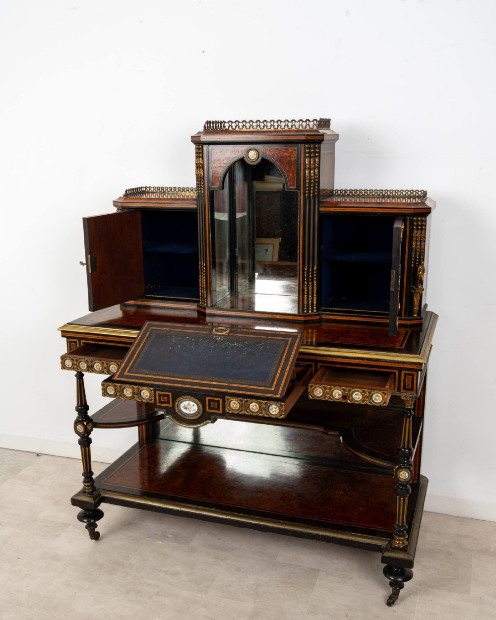 A nineteenth-century French ebonised and amboyna bonheur du jour desk featuring porcelain plaques, mirrored panels, turned legs, and brass mounts. View IX
