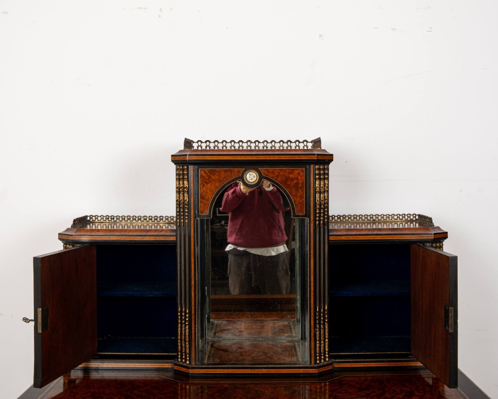 A nineteenth-century French ebonised and amboyna bonheur du jour desk featuring porcelain plaques, mirrored panels, turned legs, and brass mounts. View X
