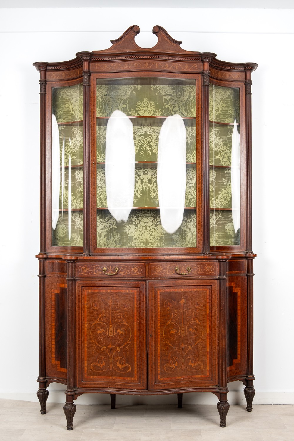 An Edwardian mahogany display cabinet featuring satinwood marquetry inlay, glazed upper doors with green fabric lining, and turned legs. View II