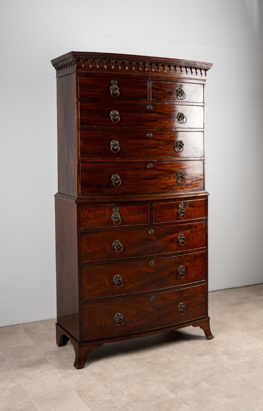 A tall Victorian bow front mahogany chest on chest featuring multiple drawer tiers with brass ring handles and upper cornice trim. View II
