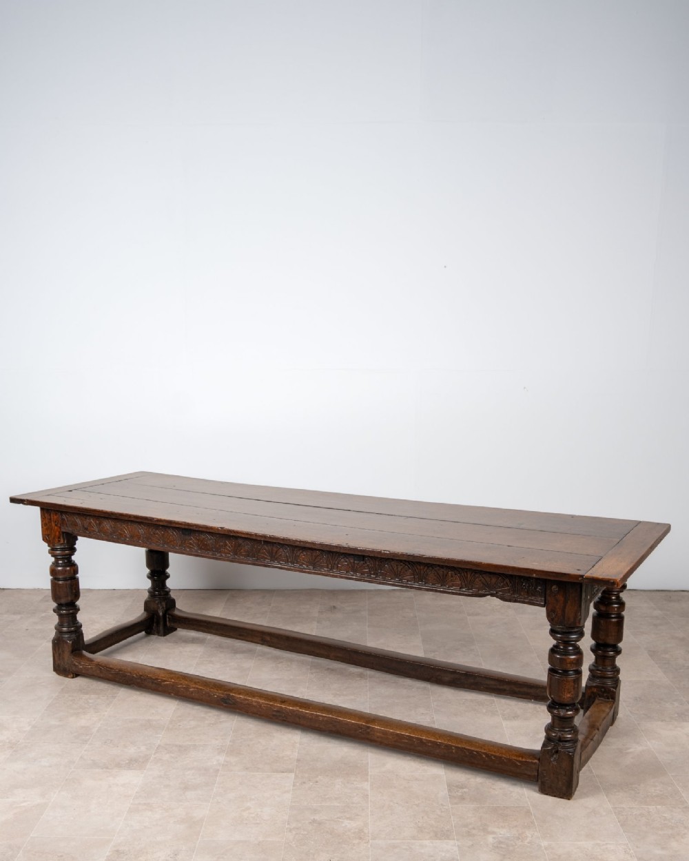 A long 18th-century oak refectory dining table featuring a carved lunette frieze, turned baluster legs, and sturdy box stretchers. View II
