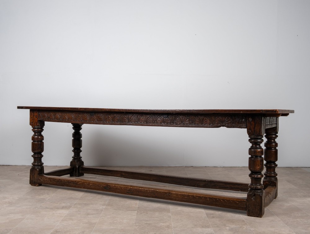 A long 18th-century oak refectory dining table featuring a carved lunette frieze, turned baluster legs, and sturdy box stretchers. View III