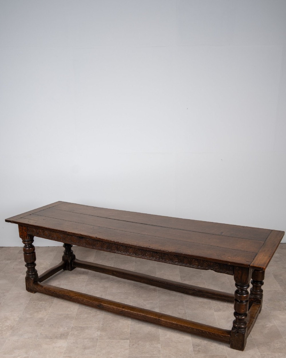 A long 18th-century oak refectory dining table featuring a carved lunette frieze, turned baluster legs, and sturdy box stretchers. View IV