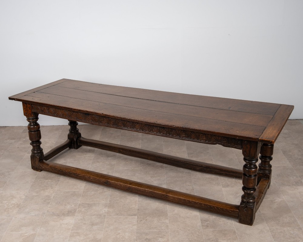 A long 18th-century oak refectory dining table featuring a carved lunette frieze, turned baluster legs, and sturdy box stretchers. View V