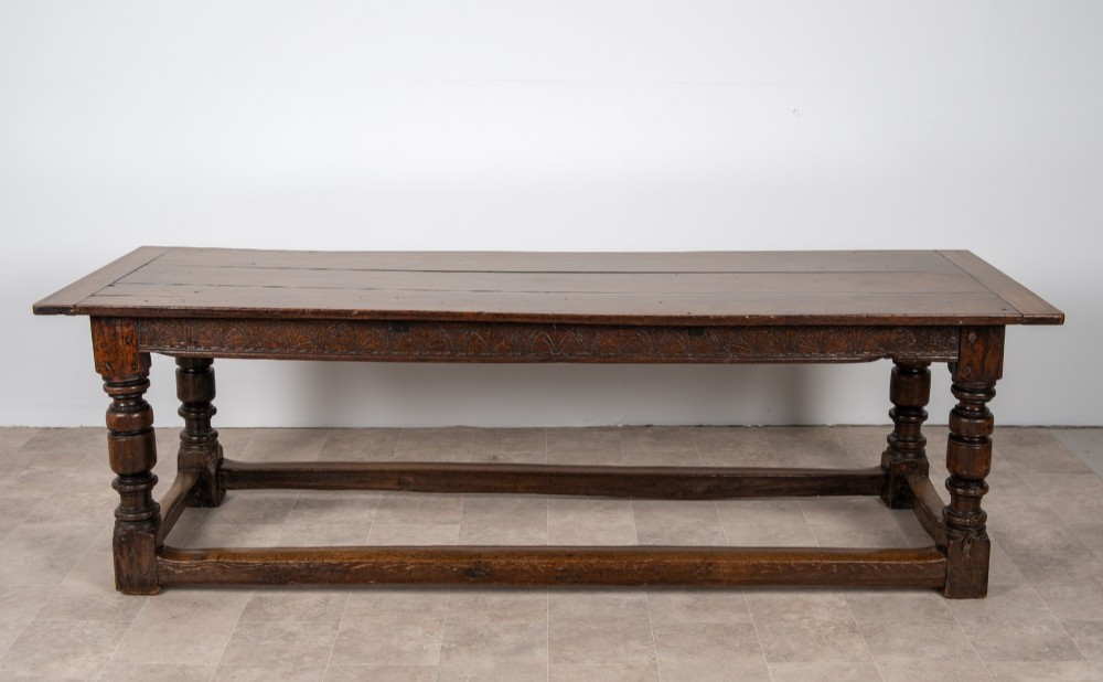 A long 18th-century oak refectory dining table featuring a carved lunette frieze, turned baluster legs, and sturdy box stretchers. View VIII