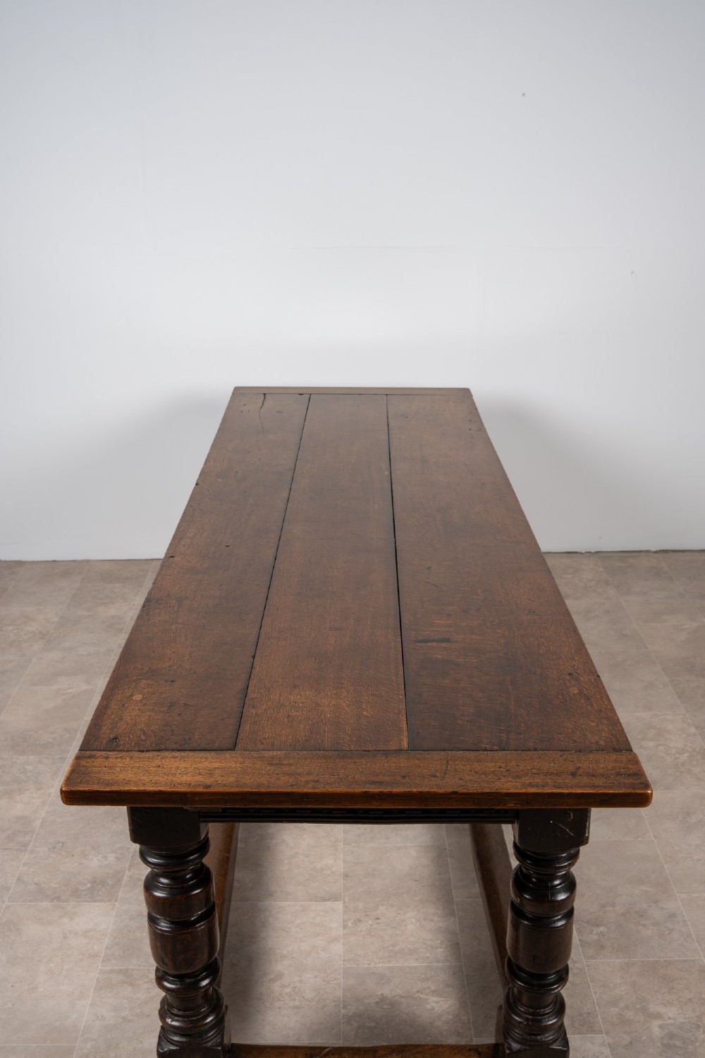 A long 18th-century oak refectory dining table featuring a carved lunette frieze, turned baluster legs, and sturdy box stretchers. View IX