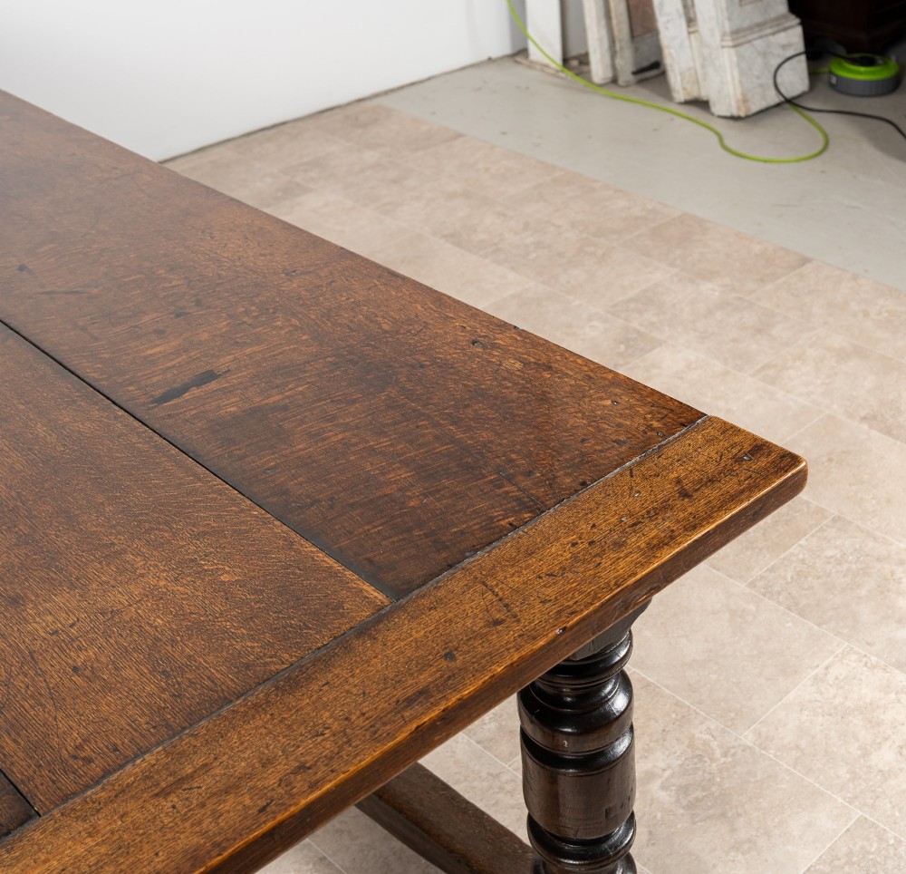 A long 18th-century oak refectory dining table featuring a carved lunette frieze, turned baluster legs, and sturdy box stretchers. View X