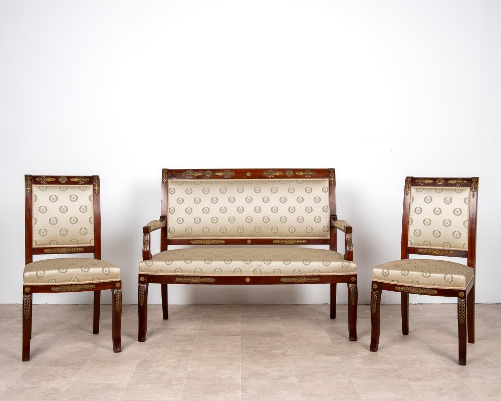 A three-piece antique French Empire Revival salon suite comprising a mahogany two-seater settee and two matching side chairs with gold silk laurel wreath upholstery and ormolu mounts. View II