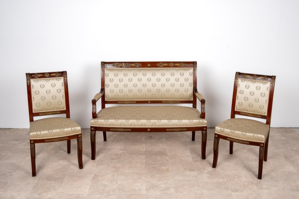 A three-piece antique French Empire Revival salon suite comprising a mahogany two-seater settee and two matching side chairs with gold silk laurel wreath upholstery and ormolu mounts. View III