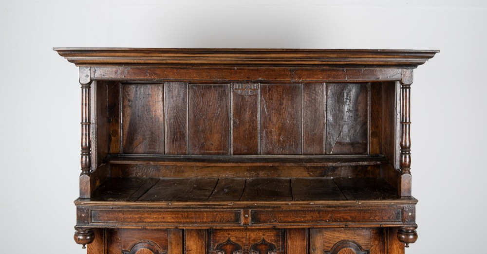 A dark oak three-tier Welsh cwpwrdd tridarn featuring an open upper canopy, middle cupboard section with raised arch panels and turned pillars, and a base cupboard with two drawers. View VIII