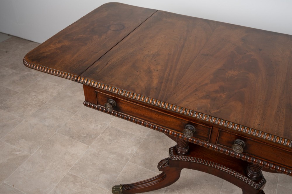 An antique Regency mahogany drop-leaf sofa table with two drawers, spiral-turned column supports, and splayed legs on brass castors. View V