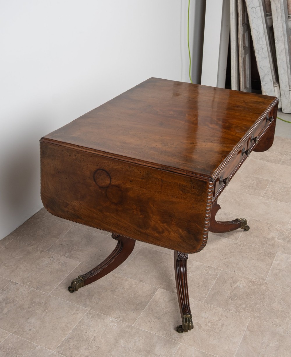 An antique Regency mahogany drop-leaf sofa table with two drawers, spiral-turned column supports, and splayed legs on brass castors. View VI