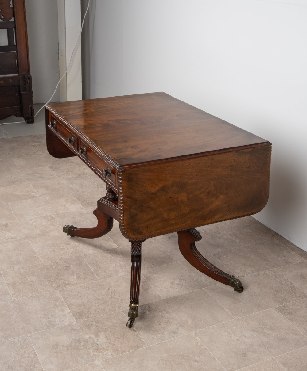 An antique Regency mahogany drop-leaf sofa table with two drawers, spiral-turned column supports, and splayed legs on brass castors. View VII