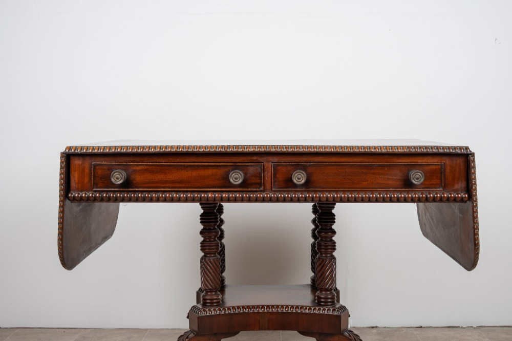 An antique Regency mahogany drop-leaf sofa table with two drawers, spiral-turned column supports, and splayed legs on brass castors. View VIII