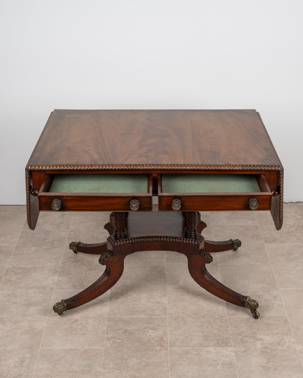 An antique Regency mahogany drop-leaf sofa table with two drawers, spiral-turned column supports, and splayed legs on brass castors. View IX