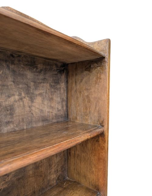 A tall, narrow warm brown oak open bookcase featuring graduated waterfall sides and seven tiers of shelving. View V