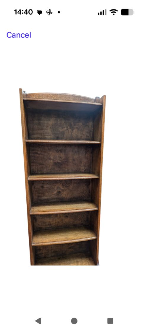 A tall, narrow warm brown oak open bookcase featuring graduated waterfall sides and seven tiers of shelving. View VI
