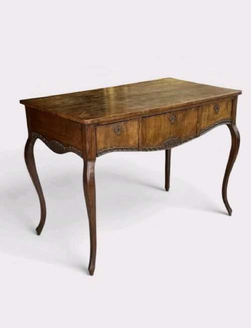fig 1. A late Victorian mahogany writing table with three drawers, brass keyhole escutcheons, and slender cabriole legs.