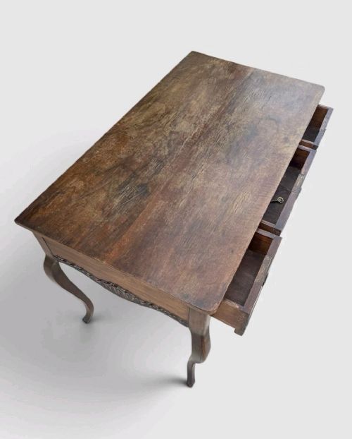 A late Victorian mahogany writing table with three drawers, brass keyhole escutcheons, and slender cabriole legs. View VI