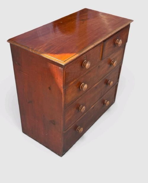 A Victorian pine chest of drawers featuring two short drawers over three long drawers with turned wooden knobs and keyholes. View X