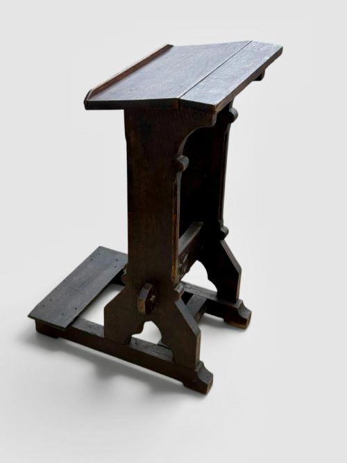 fig 2. A dark oak antique prayer desk featuring a slanted bookrest shelf, carved gothic side supports, and a built-in kneeling platform.