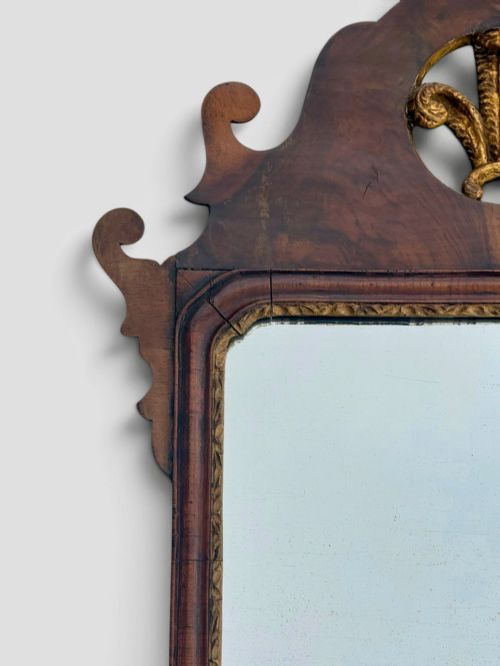 fig 2. An 18th-century Georgian wall mirror featuring a carved walnut fretwork frame with a central gilded plume motif at the top.