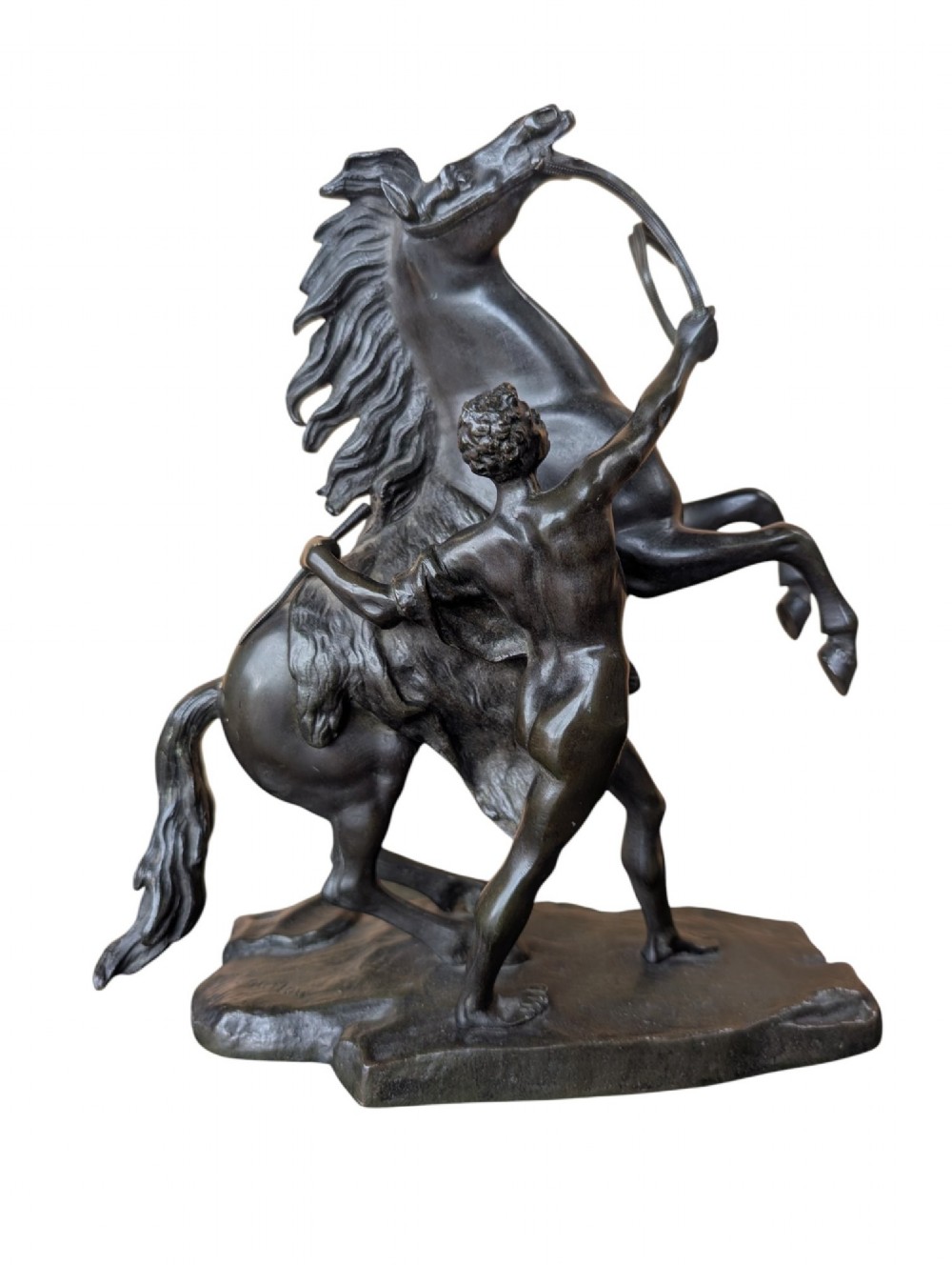 A pair of dark bronze sculptures depicting rearing horses restrained by standing grooms on naturalistic rock bases. View II