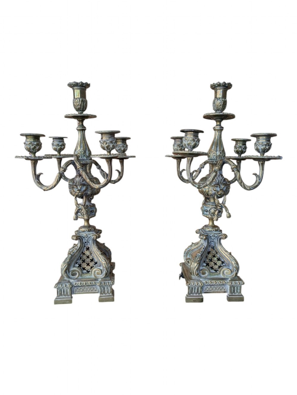 A matching pair of ornate late 19th-century patinated bronze five-light candelabra featuring lion mask motifs, scrollwork arms, and pierced decorative bases.