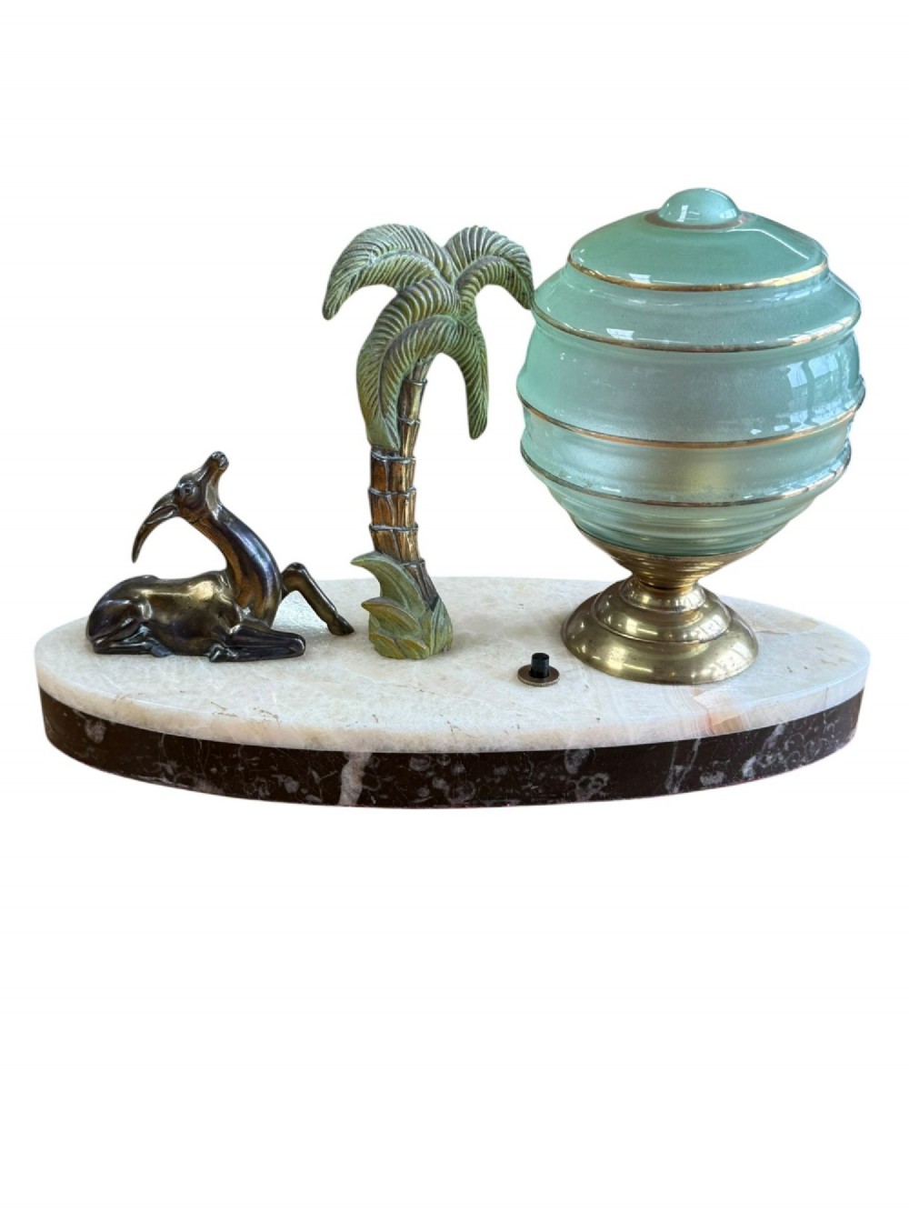 An Art Deco table lamp with a green stepped glass shade, metal palm tree, and reclining gazelle figure on an oval white marble base. View IV