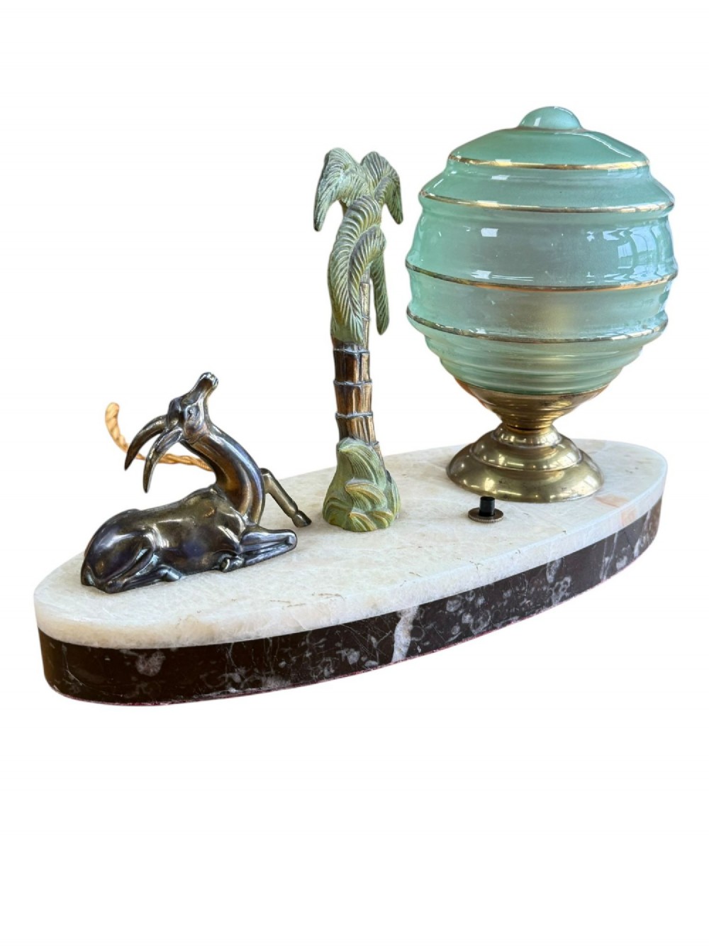 An Art Deco table lamp with a green stepped glass shade, metal palm tree, and reclining gazelle figure on an oval white marble base. View V