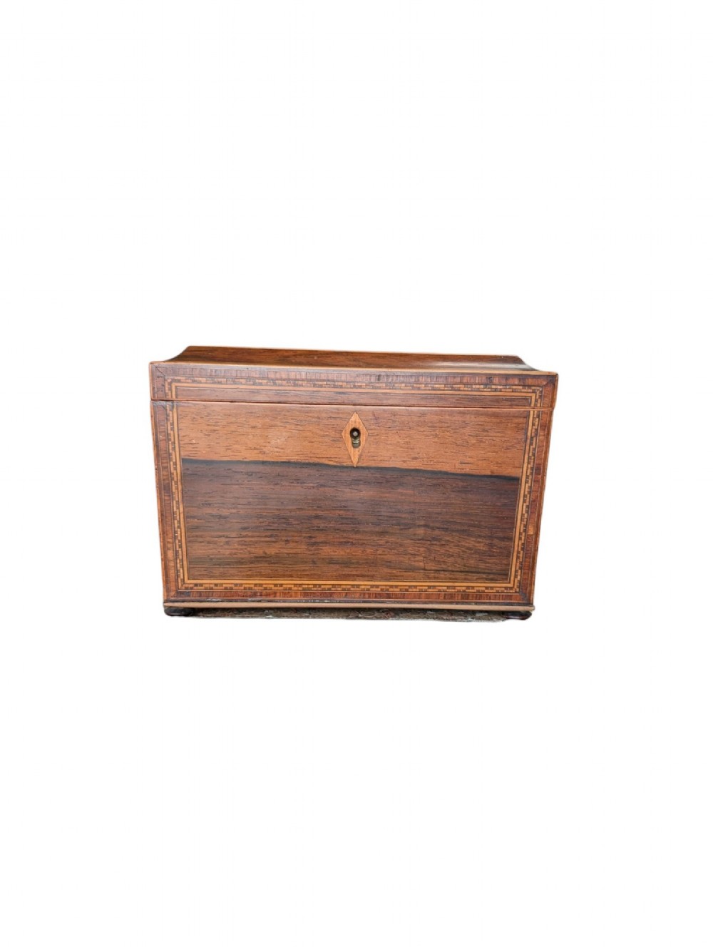 A rectangular Regency period wooden tea caddy featuring dark wood grain, mosaic inlay borders, and a central diamond escutcheon.