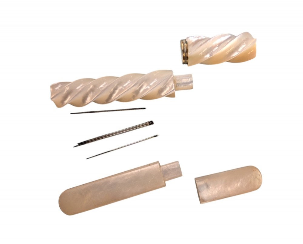 Two 19th-century mother-of-pearl needle cases, one featuring a carved spiral design and the other a smooth rectangular shape with rounded ends. View II