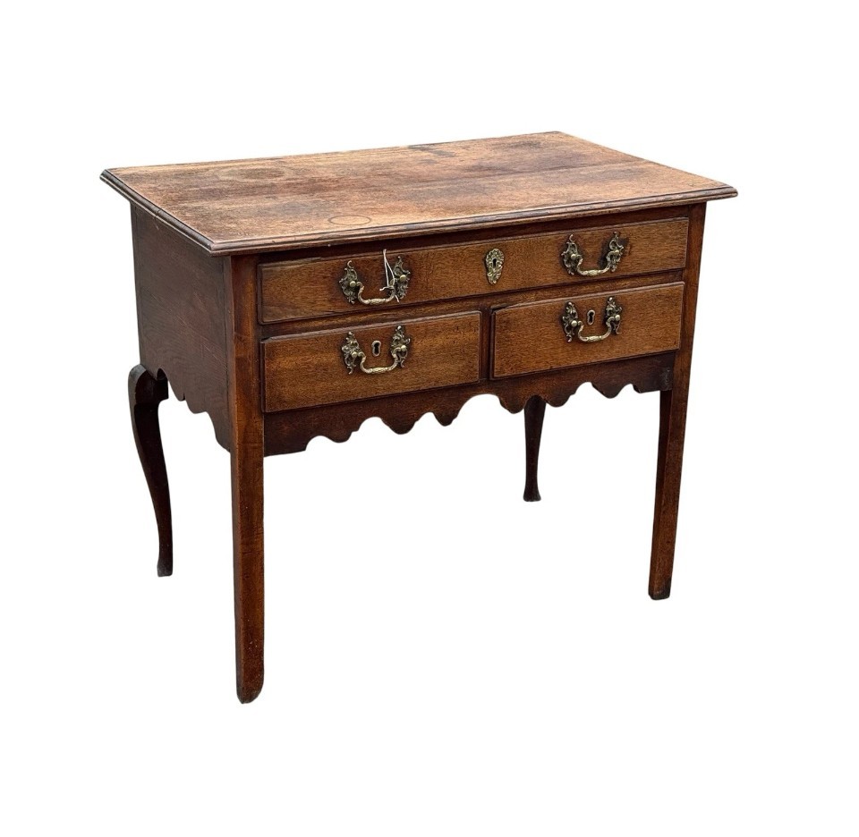 An 18th-century Georgian oak lowboy table featuring one wide upper drawer, two lower drawers, decorative brass handles, and a shaped apron. View II