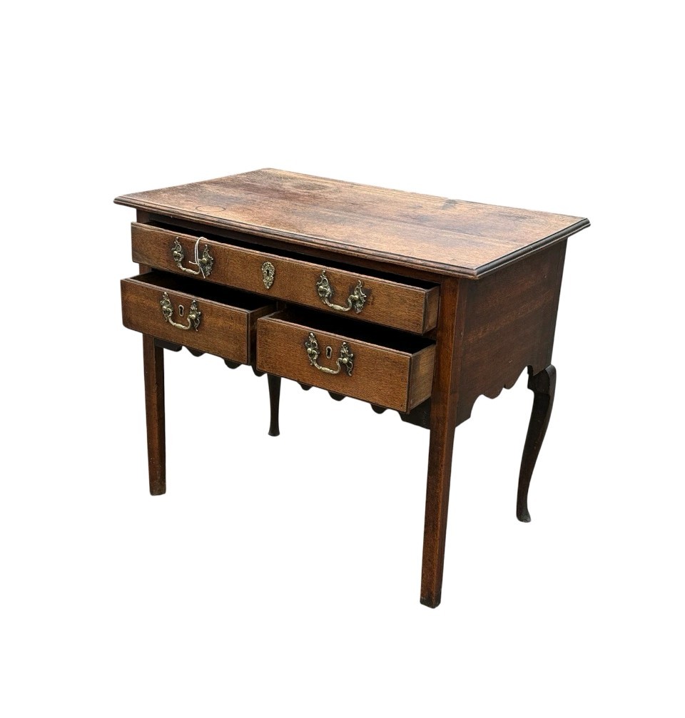 An 18th-century Georgian oak lowboy table featuring one wide upper drawer, two lower drawers, decorative brass handles, and a shaped apron. View IV