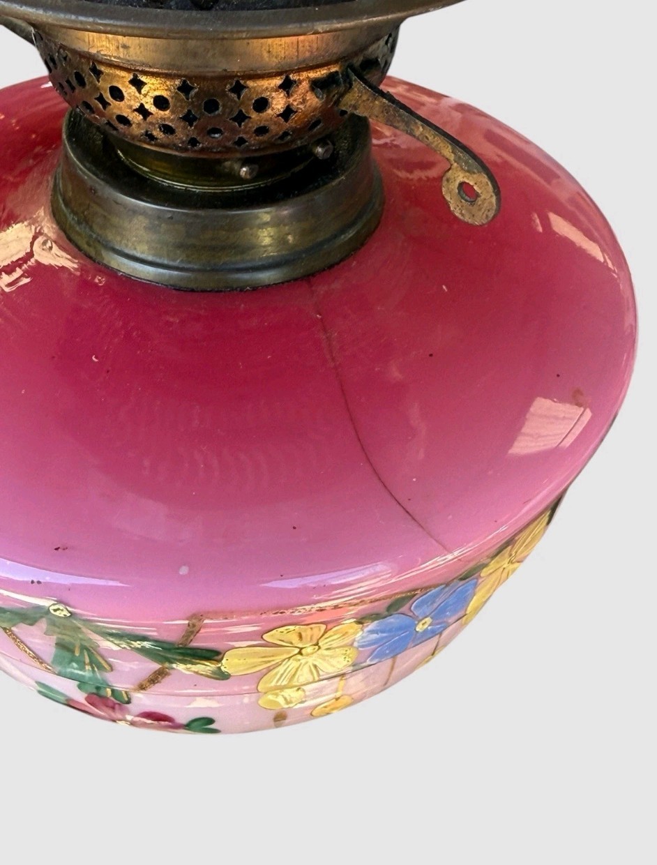 A Victorian cranberry glass oil lamp with a ruffled etched shade, hand-painted floral reservoir, brass burner, and stepped black base. View II