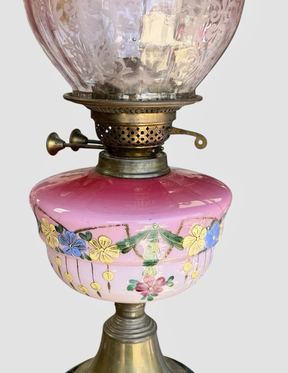 A Victorian cranberry glass oil lamp with a ruffled etched shade, hand-painted floral reservoir, brass burner, and stepped black base. View VII